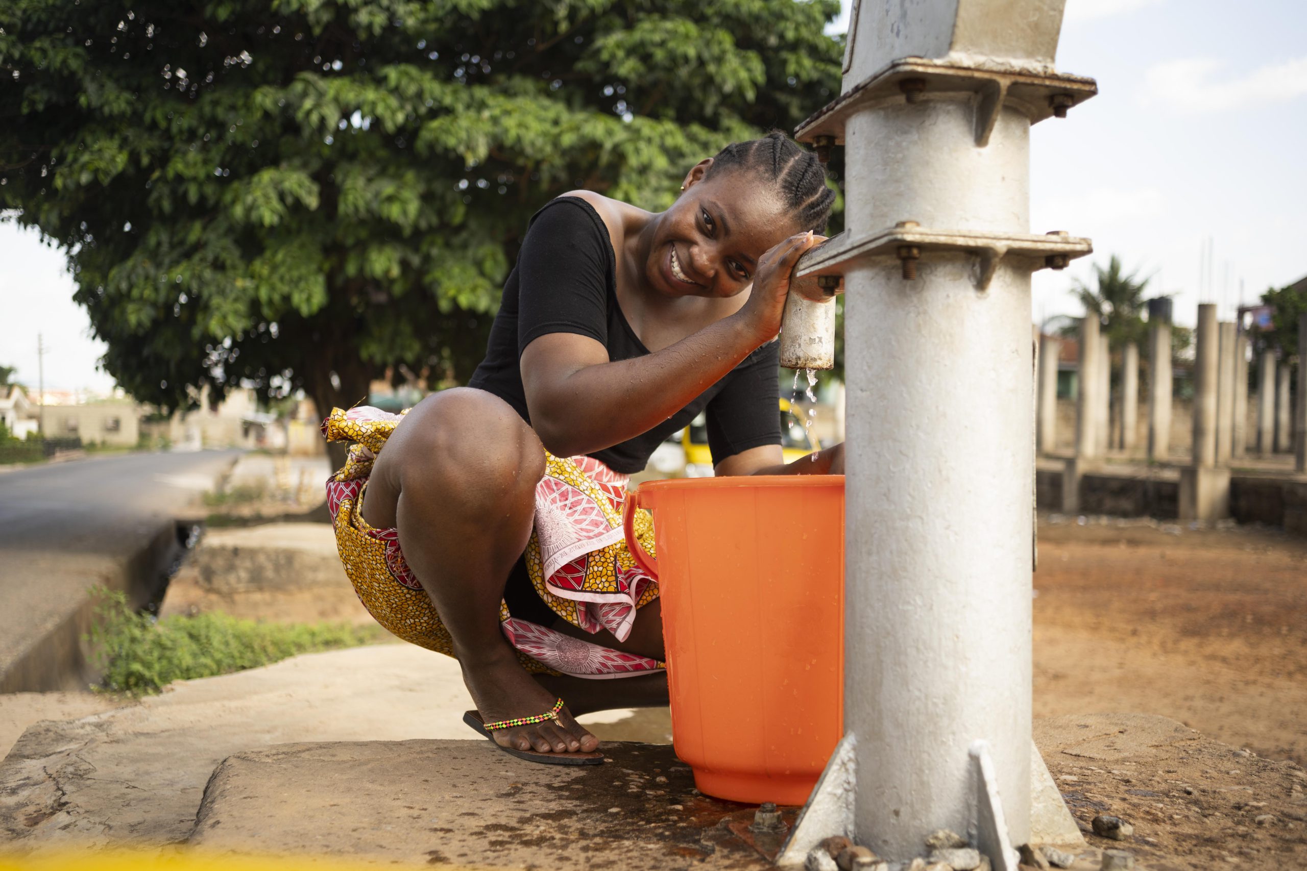 beautiful-african-woman-putting-some-water-bucket